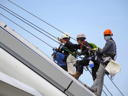 Three men safely conducting roof maintenance